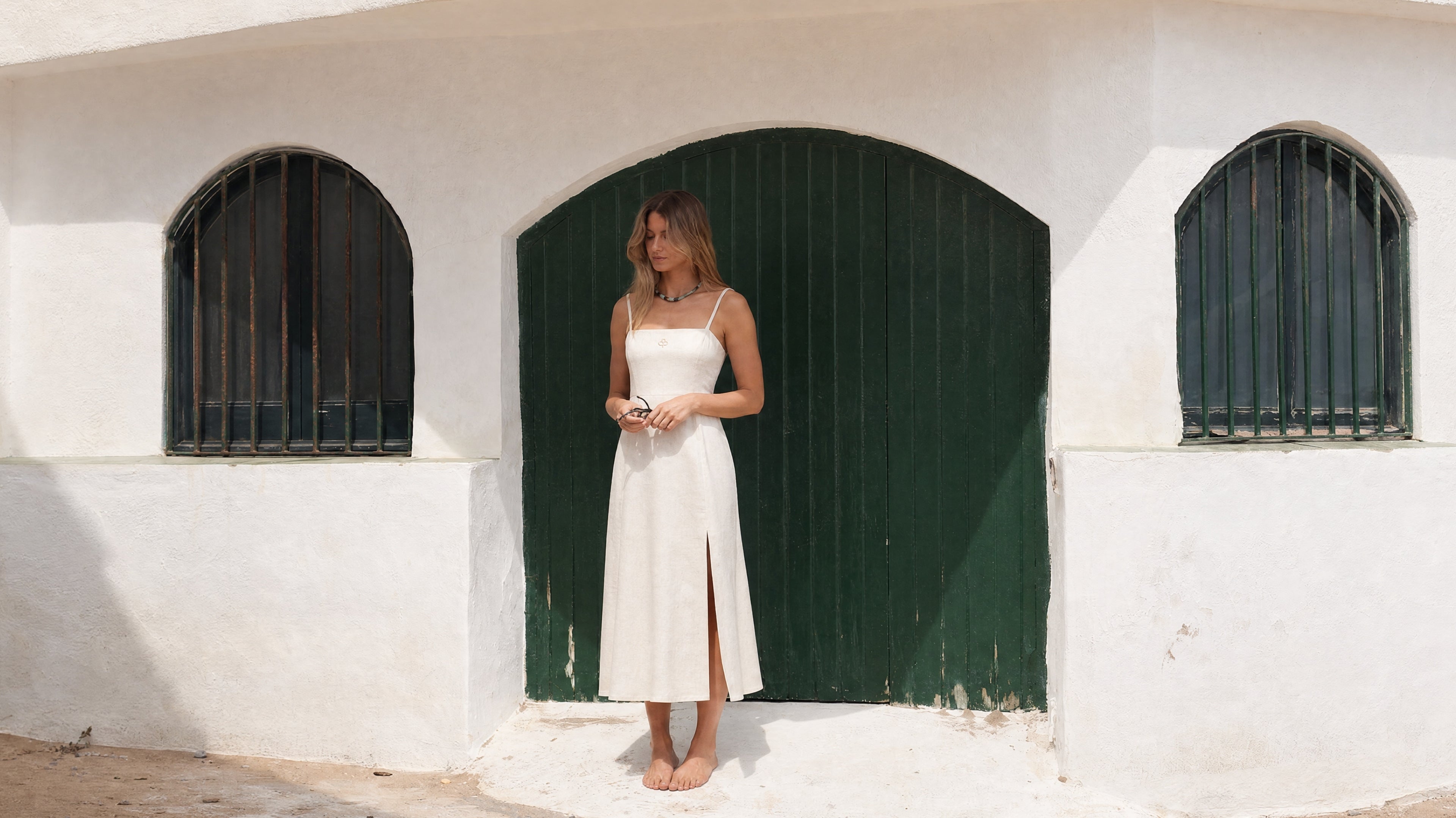 Femme portant une robe midi écrue Pamuuc en coton et lin devant des portes vertes à Garraf.