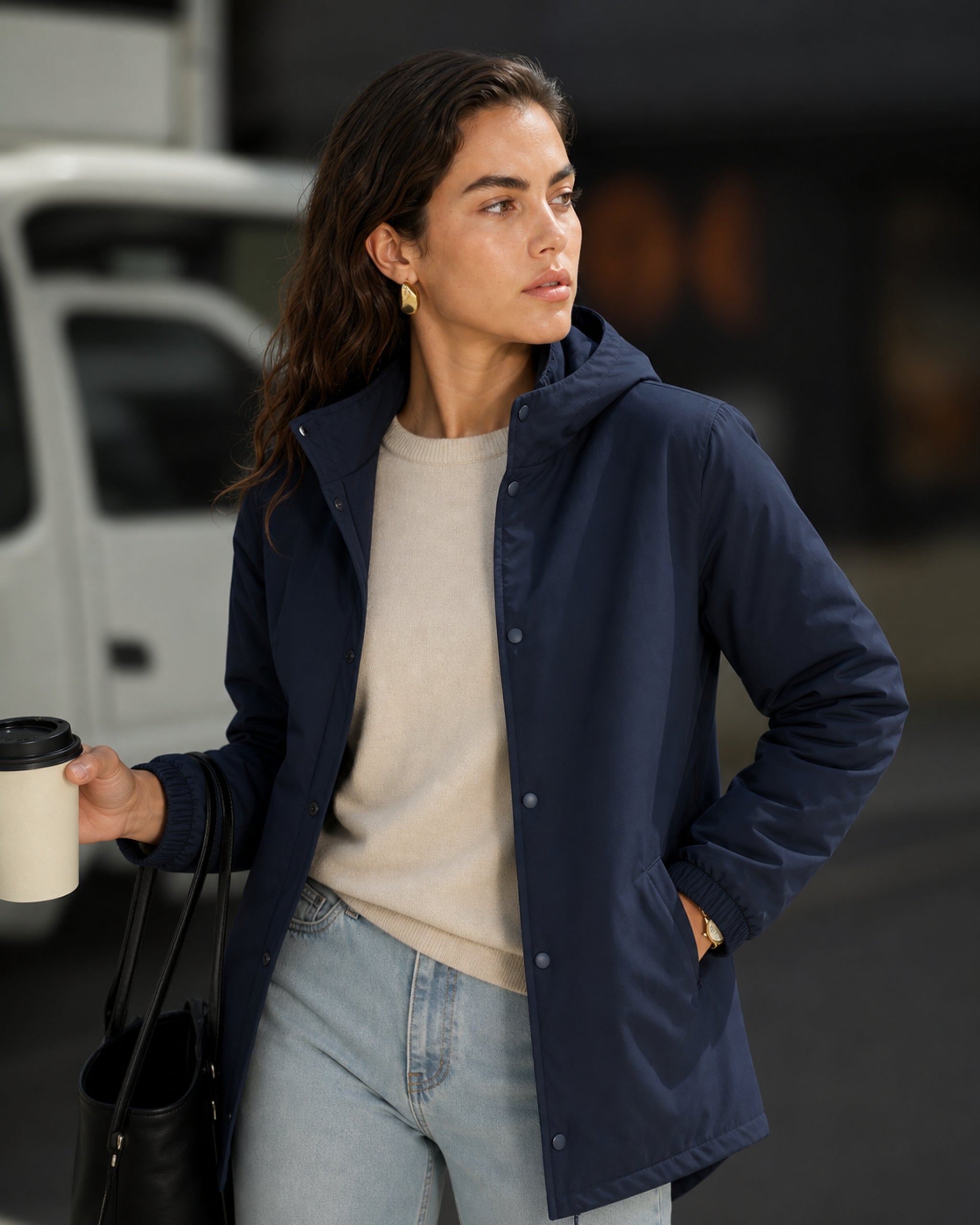 Woman in a navy padded parka holding a coffee cup on the street